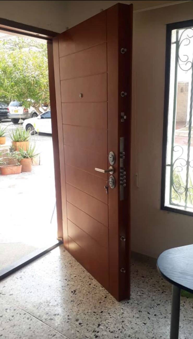 Puerta blindada en madera color cedro con sistema de cerradura multipunto y pasadores visibles