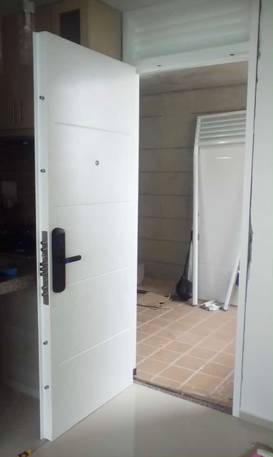 Puerta blindada blanca de gran formato con cerradura digital negra y pasadores perimetrales